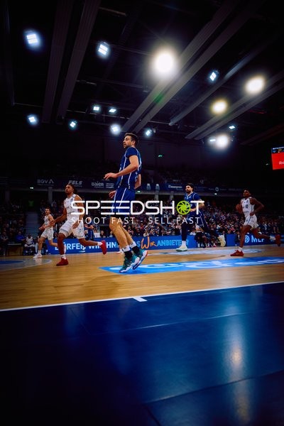 Spieler in Bewegung auf dem Spielfeld während eines Basketballspiels.