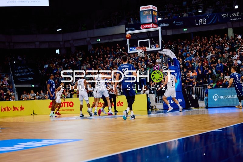 Ein Spieler von MLP Academics Heidelberg versucht, den Ball zum Korb zu bringen, während ein Spieler von Brose Bamberg verteidigt.