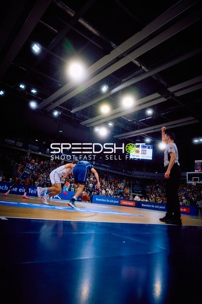 Ein Spieler in weißen Trikots verteidigt gegen einen Spieler in blauen Trikots.