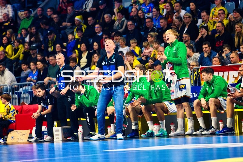 Spieler und Betreuer der HSG Wetzlar beobachten das Spiel von der Bank aus.