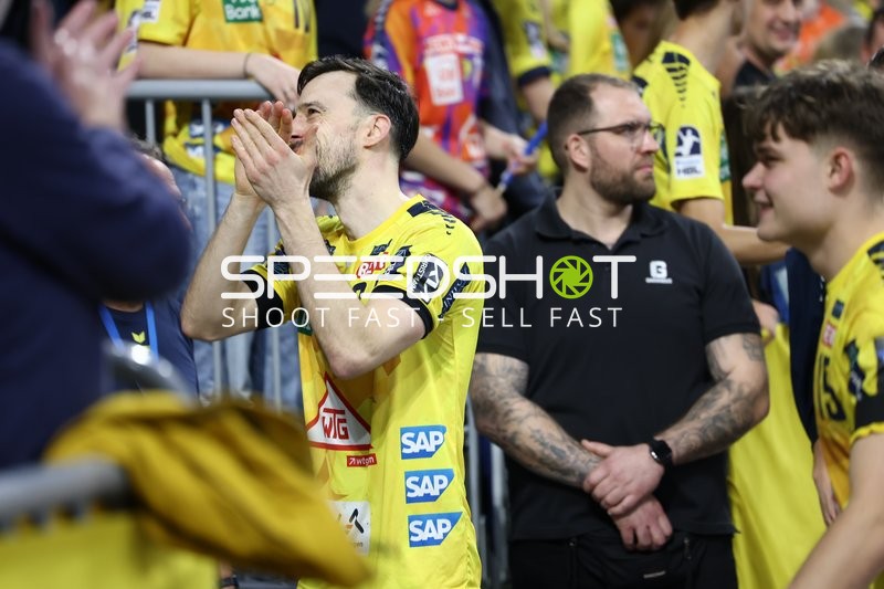 Ein Spieler der Rhein Neckar Löwen ist in Interaktion mit dem Publikum, möglicherweise applaudierend oder dankend.