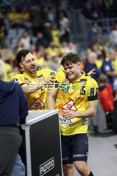 Zwei Spieler der Rhein Neckar Löwen feiern und lachen am Spielfeldrand.