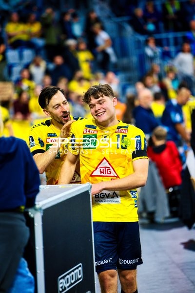 Zwei Spieler der Rhein Neckar Löwen feiern auf der Spielfeldseite.