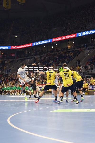 Ein Spieler von HSG Wetzlar springt in die Luft, während Spieler der Rhein Neckar Löwen verteidigen.