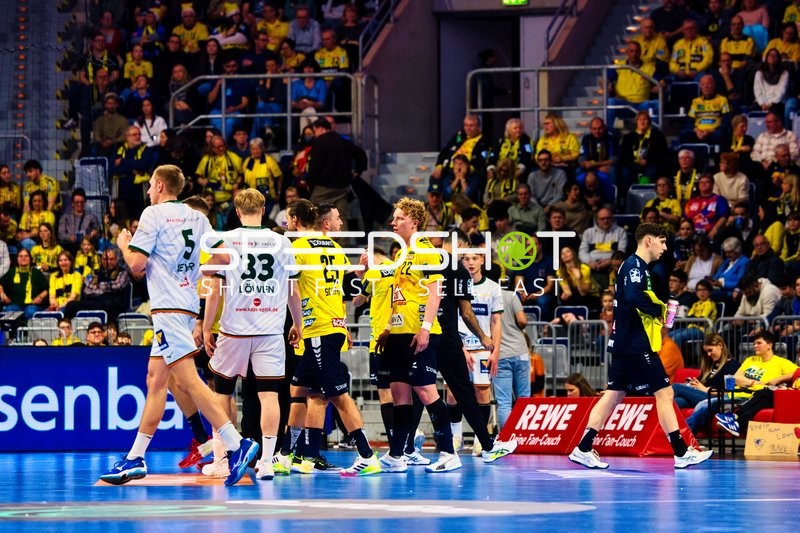 Spieler auf dem Spielfeld während einer Handballpartie, möglicherweise in Vorbereitung auf eine Spielaktion.