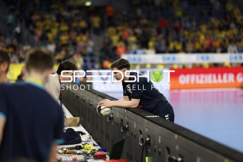 Ein Spieler lehnt sich über die Bande und spricht mit jemandem am Spielfeldrand.