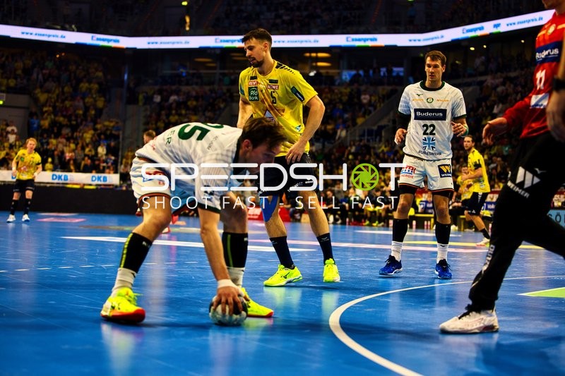 Jona Schoch von HSG Wetzlar beugt sich, um den Ball aufzunehmen, während David Späth von Rhein Neckar Löwen die Situation beobachtet.