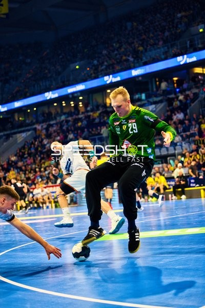 Ein Spieler in grünem Trikot (Nummer 29) von HSG Wetzlar springt und kontrolliert den Ball auf dem Spielfeld.