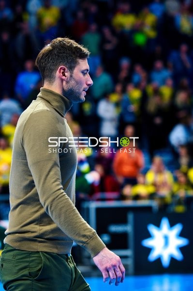 Eine Person im Vordergrund geht am Spielfeldrand entlang.