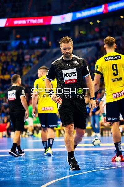 Ein Schiedsrichter auf dem Spielfeld, während Spieler von Rhein Neckar Löwen zu sehen sind.