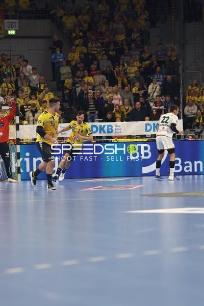 Rhein Neckar Löwen Spieler in gelben Trikots laufen aufs Tor zu, während HSG Wetzlar Spieler in weißem Trikot verteidigt.