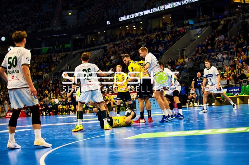 Ein Spieler von Rhein Neckar Löwen liegt auf dem Boden, während ein Spieler von HSG Wetzlar verteidigt.