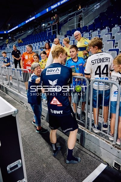 Ein Spieler von THW Kiel unterschreibt Autogramme für Fans.
