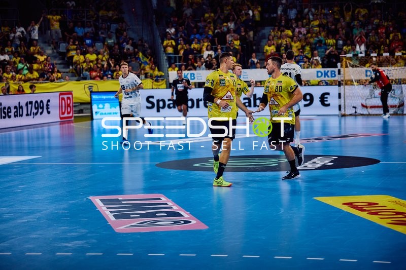 Zwei Spieler der Rhein Neckar Löwen feiern auf dem Spielfeld.