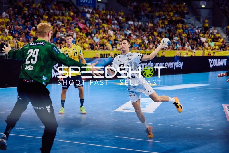 Ein Spieler von THW Kiel springt zum Wurf, während der Torwart von Rhein Neckar Löwen bereit ist, zu verteidigen.