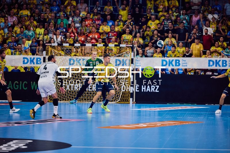 Ein Spieler von Rhein Neckar Löwen versucht, an einem gegnerischen Verteidiger vorbeizukommen, während der Torwart in Position ist.