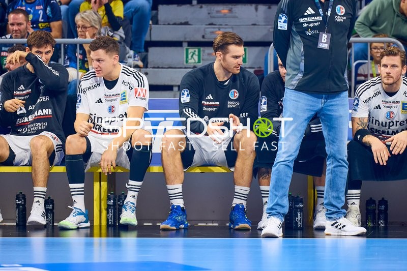 Spieler von THW Kiel sitzen auf der Auswechselbank und beobachten das Spielgeschehen.