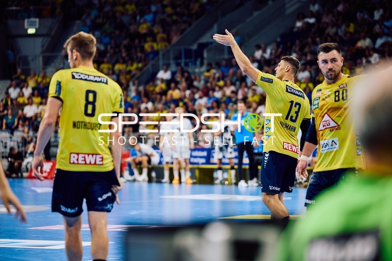 Ein Spieler der Rhein Neckar Löwen signalisiert eine Aktion, während die anderen Spieler aufmerksam sind.