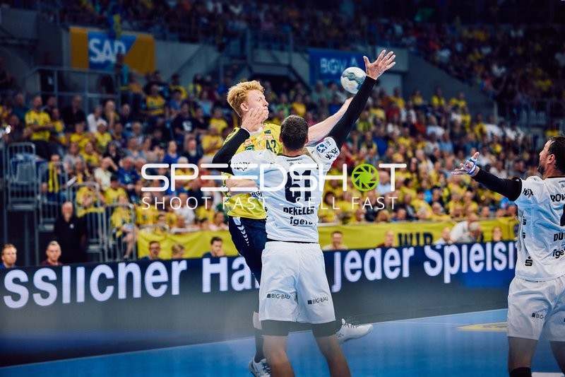 Ein Spieler von Rhein Neckar Löwen versucht, den Ball zu werfen, während ein Verteidiger von THW Kiel ihn blockiert.