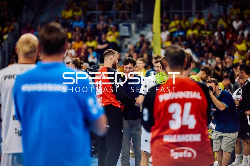 Spieler von Rhein-Neckar Löwen und THW Kiel stehen zusammen auf dem Spielfeld.