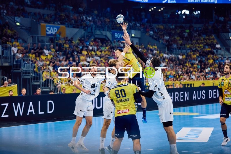 Ein Spieler von Rhein Neckar Löwen springt, um einen Wurf zu machen, während Spieler von THW Kiel versuchen zu blocken.