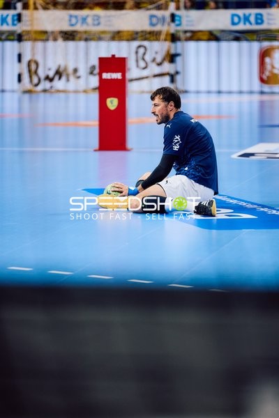 Ein Spieler sitzt mit einem Ball auf dem Spielfeld.