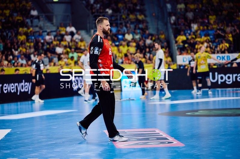 Ein Spieler in einem roten Trikot steht auf dem Spielfeld.