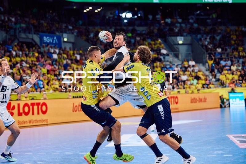 Ein Spieler von THW Kiel versucht, den Ball gegen zwei Spieler der Rhein Neckar Löwen zu werfen.