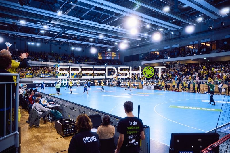 Ein Handballspiel findet in einem vollbesetzten Stadion statt.