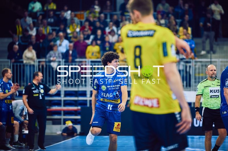 Ein Spieler von ThSV Eisenach läuft auf das Spielfeld, während ein Spieler von Rhein Neckar Löwen im Vordergrund sichtbar ist.