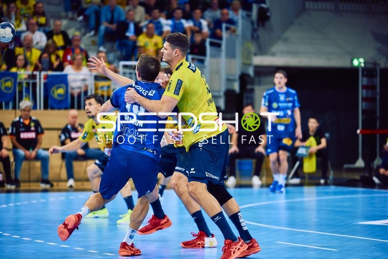 Ein Spieler der Rhein Neckar Löwen im gelben Trikot versucht, einen Spieler von ThSV Eisenach zu blockieren.