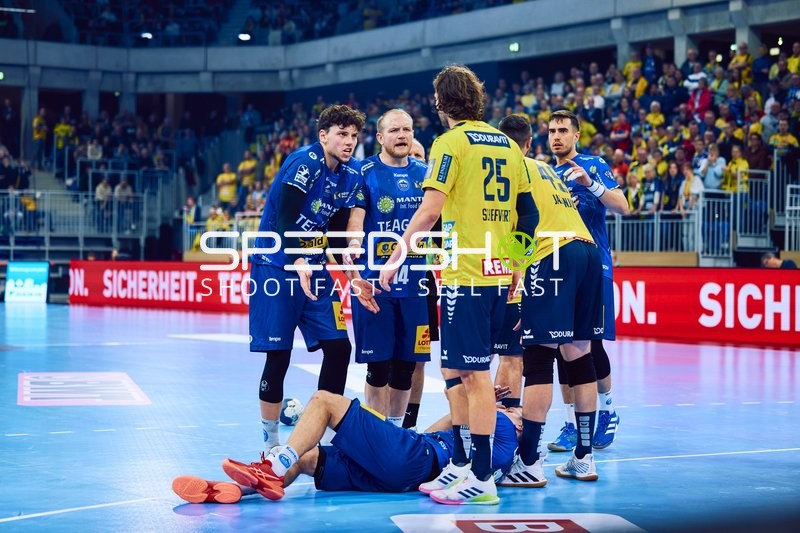 Ein Spieler von Rhein Neckar Löwen hilft einem gefallenen Spieler von ThSV Eisenach auf.