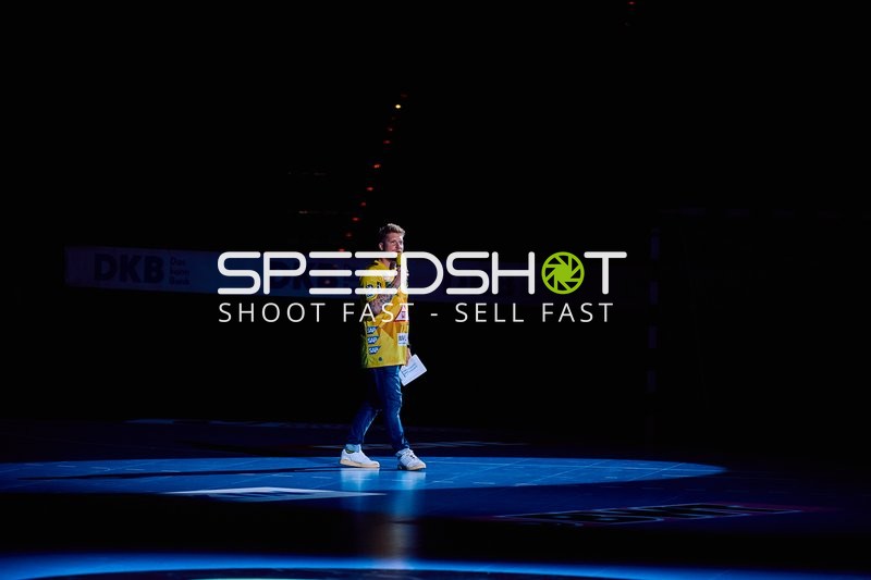 Ein Moderator steht im Rampenlicht auf dem Spielfeld.