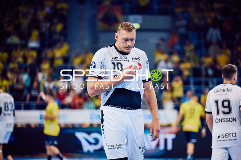 Ein Spieler von MT Melsungen mit der Nummer 10 schaut nach unten und hält sein Trikot.