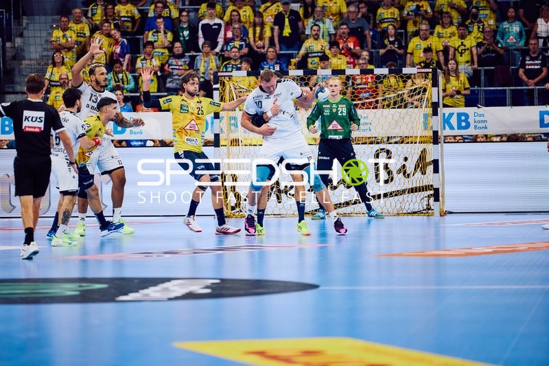 Ein Spieler von Rhein Neckar Löwen greift zum Tor an, während MT Melsungen in der Verteidigung steht.