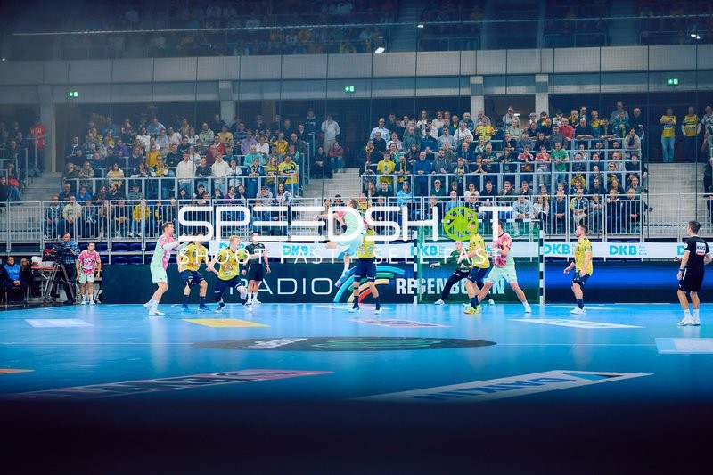 Ein Spieler von Rhein Neckar Löwen springt zum Wurf, während die Verteidiger von Füchse Berlin versuchen, den Angriff zu blocken.