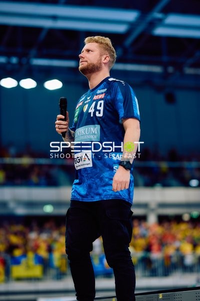 Spieler der Rhein Neckar Löwen mit Mikrofon in der Hand auf dem Spielfeld.
