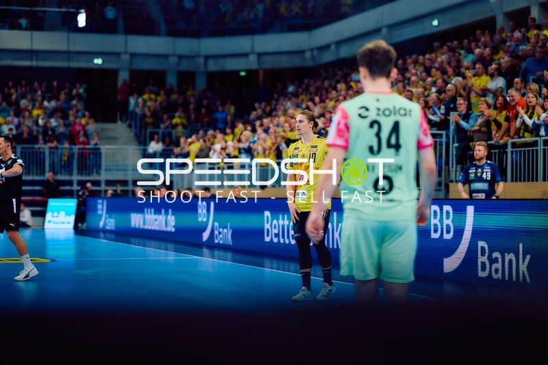 Spielunterbrechung am Spielfeldrand mit zwei Spielern im Vordergrund.