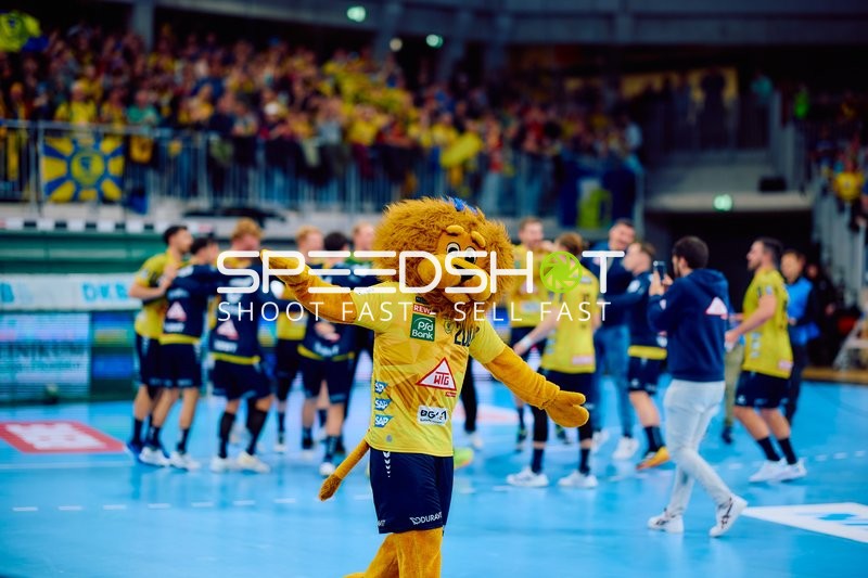 Ein Maskottchen auf dem Spielfeld feiert mit den Fans im Hintergrund.