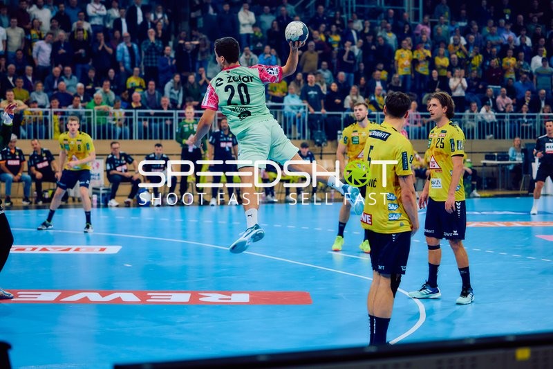 Ein Spieler von Füchse Berlin springt zum Wurf, während Spieler von Rhein Neckar Löwen verteidigen.