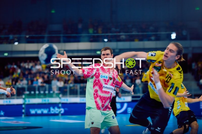 Juri Knorr von den Rhein Neckar Löwen wirft den Ball in einem Angriffsspielzug, während Max Beneke von den Füchsen Berlin verteidigt.