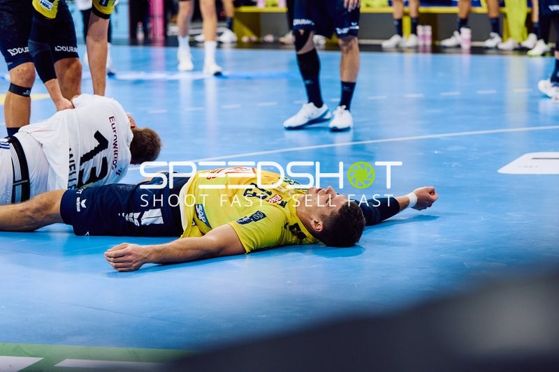 Ein Spieler der Rhein Neckar Löwen liegt auf dem Boden, während ein Spieler von HSV Hamburg in seiner Nähe ist.