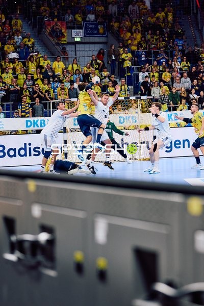 Ein Spieler der Rhein Neckar Löwen versucht, ein Tor zu werfen, während Spieler des HSV Hamburg verteidigen.