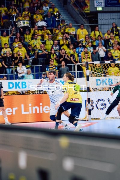 Ein Spieler von HSV Hamburg versucht, den Ball Richtung Tor zu werfen, während ein Spieler der Rhein Neckar Löwen verteidigt.