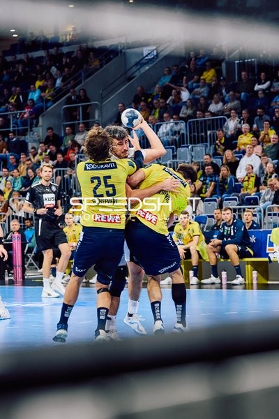 Zwei Spieler von Rhein Neckar Löwen versuchen, den Ballbesitzer von HSV Hamburg am Torschuss zu hindern.