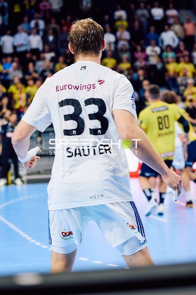 Ein Spieler von HSV Hamburg, nummeriert 33, ist in defensiver Position vor einem Spieler von Rhein Neckar Löwen mit der Nummer 80.