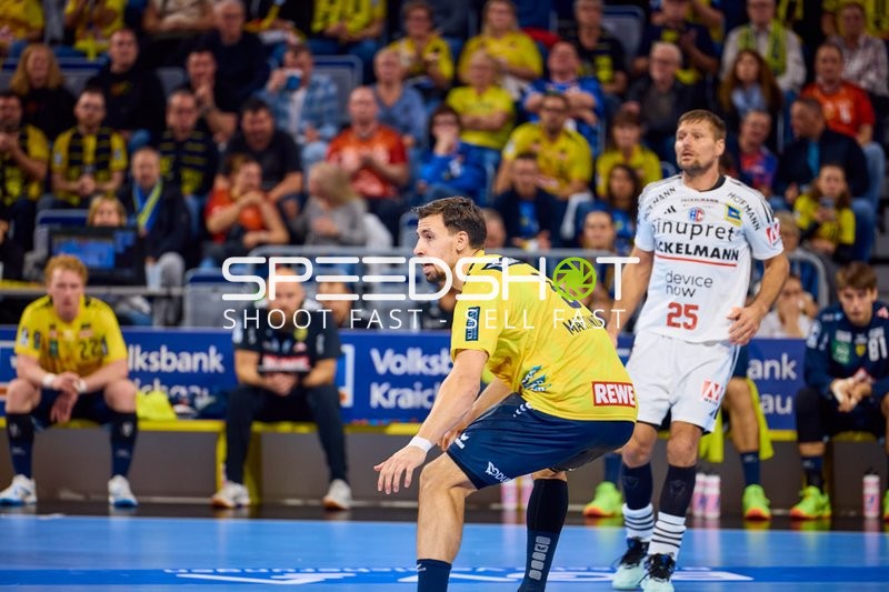 Spieler von Rhein Neckar Löwen konzentriert sich auf den Ball, während Marko Bezjak von HC Erlangen im Hintergrund steht.