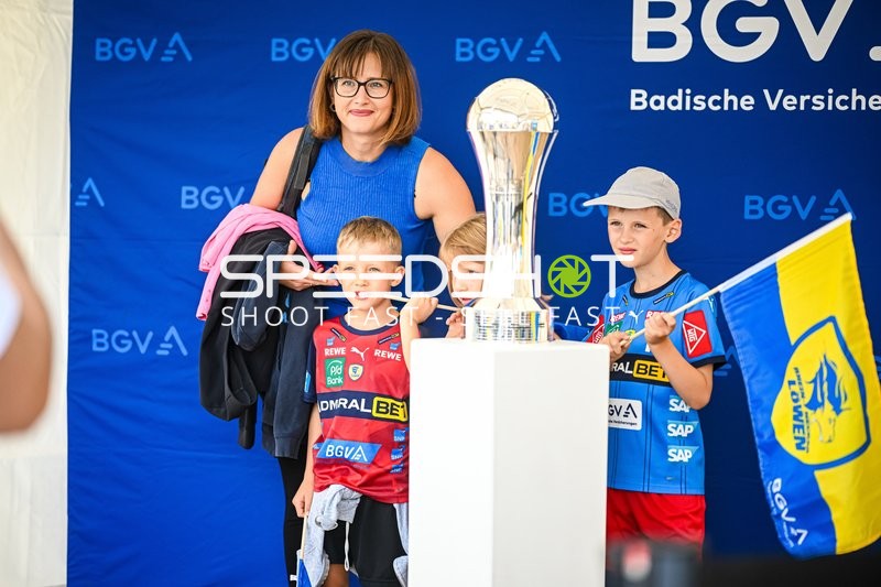 Fans posieren mit einem Pokal und halten Fahnen der Rhein Neckar Löwen.
