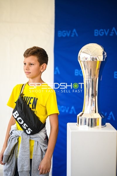 Ein Junge posiert neben einer Trophäe.