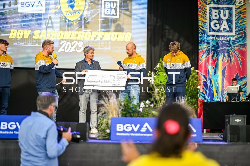 Übergabe eines großen Schecks auf der Bühne während der Saisoneröffnung.